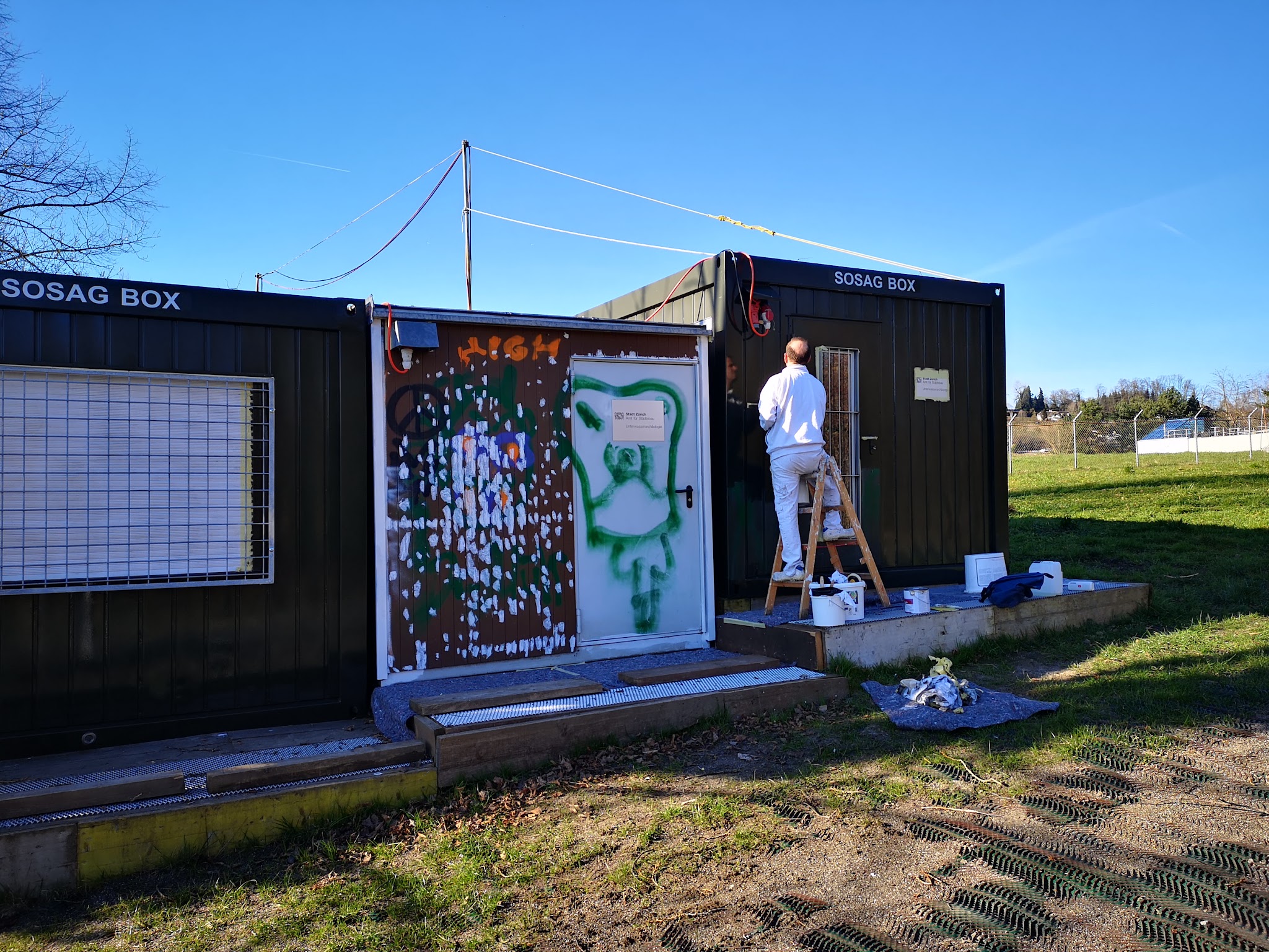 Maler bemalt einen Container im Freien mit einem Wandbild